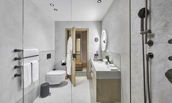 Badezimmer Deluxe Studio Sailer Modernes Badezimmer mit Waschtisch, WC und Dusche in Grau- und Holztönen.