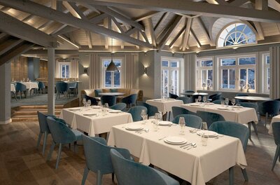 Ein modernes Restaurant mit eleganten Tischen und blauen Stühlen. Große Fenster erlauben viel natürliches Licht und bieten einen schönen Ausblick.