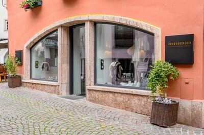 Außenansicht des Sinnesberger Fashionstores mit Schaufenstern in einer gepflasterten Gasse.