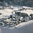 Winterlandschaft in Jochberg bei Kitzbühel mit Dorf, Bergen und Nadelbäumen.