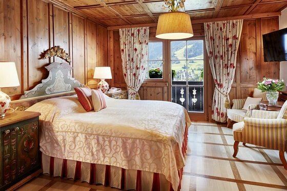 Wohnen im Hotel Tennerhof Rustikales Hotelzimmer mit Doppelbett, Holzvertäfelung und Blick auf die Berge.