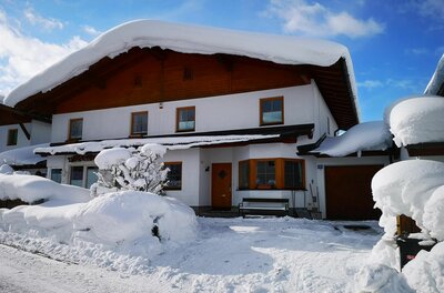 Winteransicht Haus Aschenwald Zweistöckiges Wohnhaus mit holzverkleidetem Giebel und einer dicken Schneeschicht auf dem Dach.