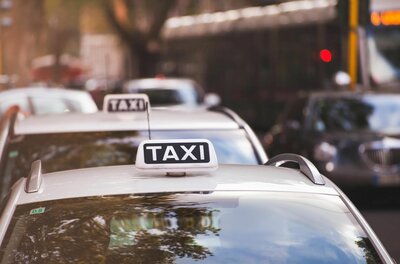 Taxi Mimm Service Nahaufnahme eines weißen Taxischilds auf einem Autodach in einer Reihe wartender Fahrzeuge.