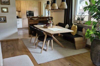 Wohnraum Haus Egger Moderner Essbereich mit Holztisch, Sitzbank und Stühlen unter einer Kassettendecke aus Holz.
