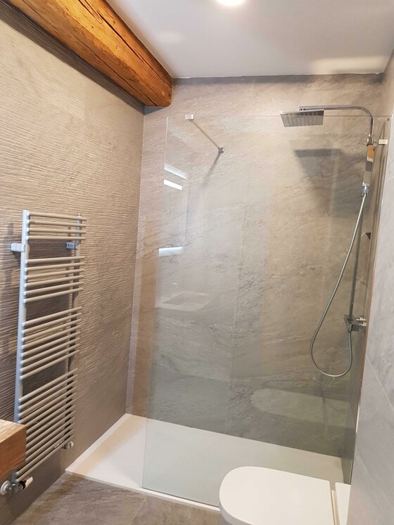 Badezimmer Apartment Südberge Modernes Badezimmer mit begehbarer Glasdusche, Handtuchheizkörper und Holzbalken an der Decke.