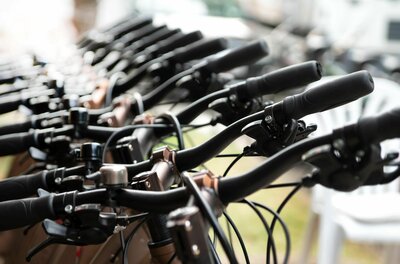 Nahaufnahme einer Reihe von Fahrradlenkern mit schwarzen Griffen und Bremshebeln.