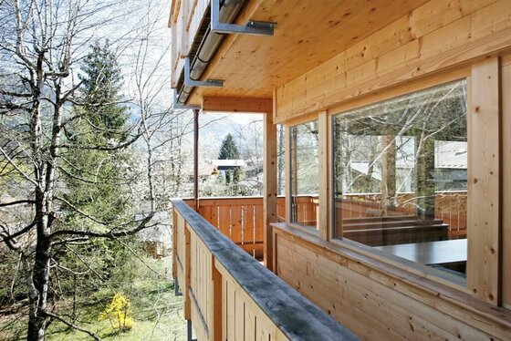 Balkon des Hotel Garni Christophorus Holzbalkon eines Gebäudes mit Blick auf Bäume und angrenzende Häuser.