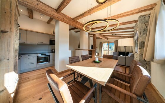 Essbereich Wagstätt Residenz Jochberg Moderner Essbereich mit Holztisch und Lederstühlen vor einer offenen Küche in einer alpinen Ferienwohnung.