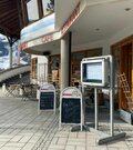 Außenansicht des Restaurants Hornplatzl mit Terrasse, Speisekartenaushängen und Blick auf verschneite Berge.