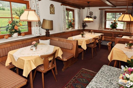 Frühstücksraum im Mühlbergerhof Rustikaler Gastraum mit hölzernen Eckbänken, gedeckten Tischen und traditionellen Hängelampen.