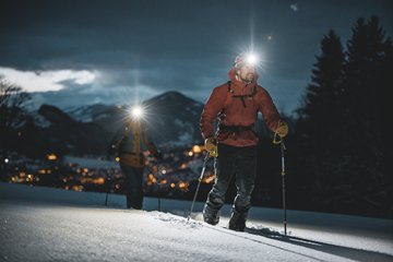 Zwei Skitourengeher mit Stirnlampe