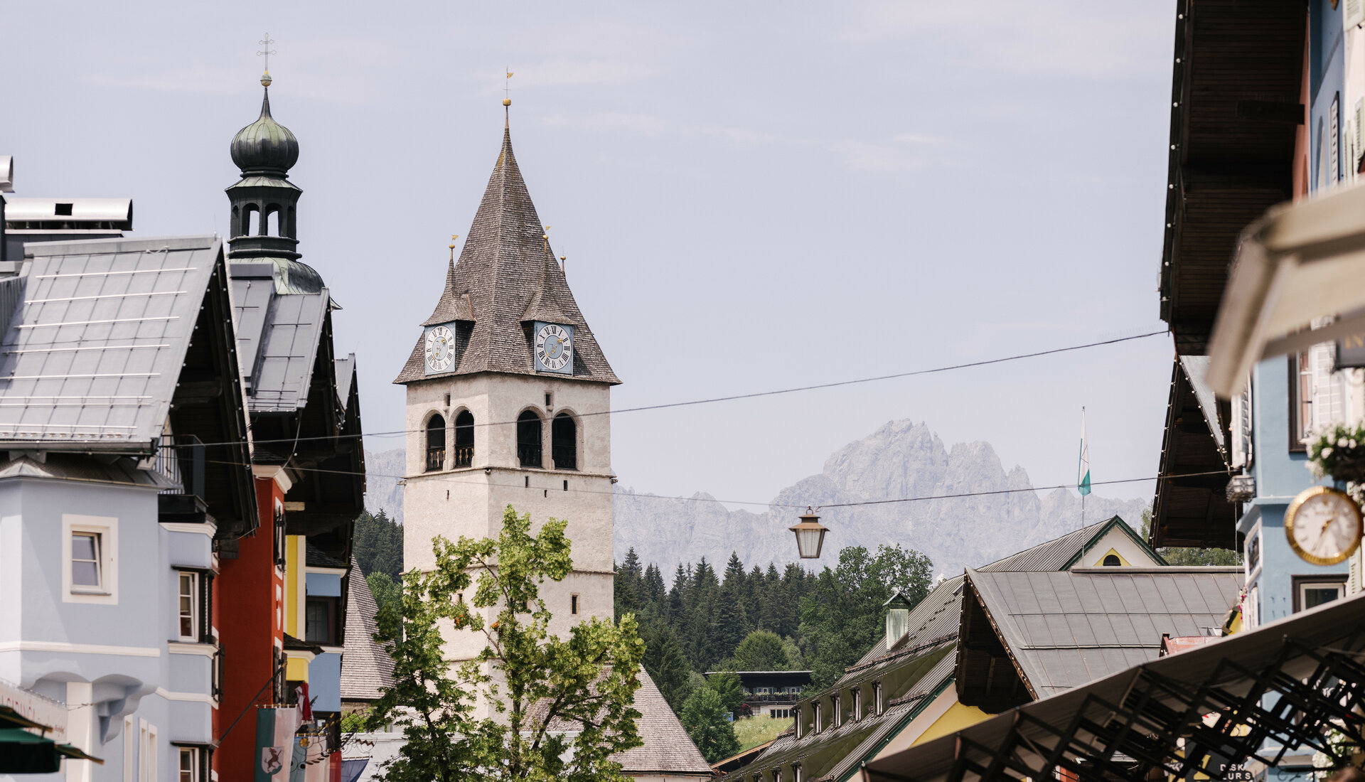 Ein malerischer Blick auf eine Stadt mit einem markanten Kirchturm und bunten Gebäuden im Vordergrund.