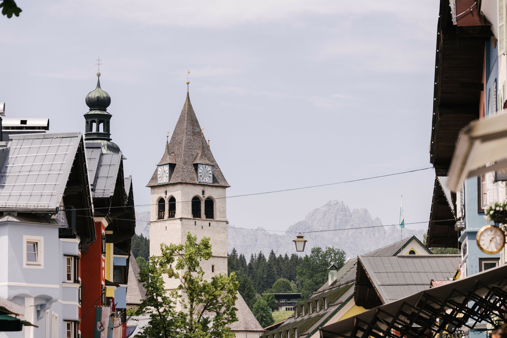 Ein malerischer Blick auf eine Stadt mit einem markanten Kirchturm und bunten Gebäuden im Vordergrund.