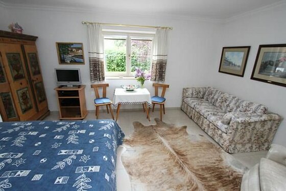 Zimmer Jasmin im Haus Wohn- und Schlafraum mit Doppelbett, Sofa, Esstisch und rustikalem Schrank.