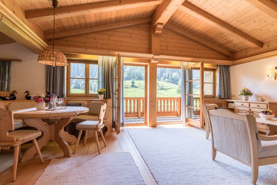 Wohnbereich der Ferienwohnung Neuhaus Heller Wohnraum aus Holz mit Esstisch, Sitzecke und Balkonzugang in einer Ferienwohnung.