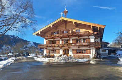 20260115_132644 Ein traditionelles Chalet im Winter, umgeben von Schnee. Der Himmel ist blau und die Landschaft ist malerisch.