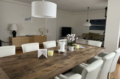 Essbereich im Haus Beatrice Rustikaler Holztisch mit weißen Lederstühlen in einem hellen Esszimmer.