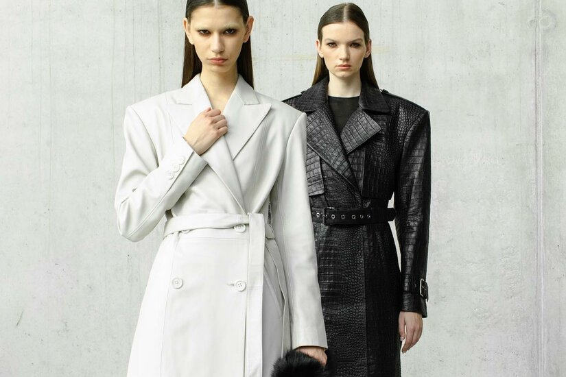 Farah Kimia Modepräsentation Zwei Models in langen Mänteln vor einer Betonwand.