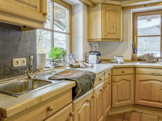 Helle Holzküche mit Spülbecken, Kaffeemaschine und Fenster mit Blick auf die Berge.