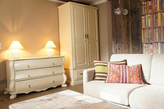 Wohnzimmer mit hellem Sofa, Kommode, Schrank und Wandgestaltung in Holzoptik.