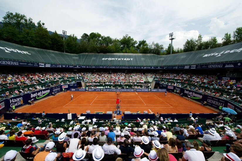 Tennisstadion Kitzbühel Blick von der Tribüne auf einen Sand-Tennisplatz während eines Turniers mit vielen Zuschauern.