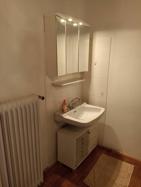 Badezimmer City Kitz 4 Badezimmer mit weißem Waschbecken, Spiegelschrank und Heizkörper.