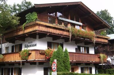 Mehrstöckiges Gebäude mit Holzfassade, Balkonen und Blumenkästen unter einem Satteldach.