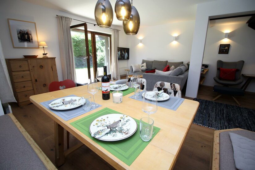 Gedeckter Holztisch in einem modernen Wohn- und Essbereich mit Sofa und Terrassenzugang.