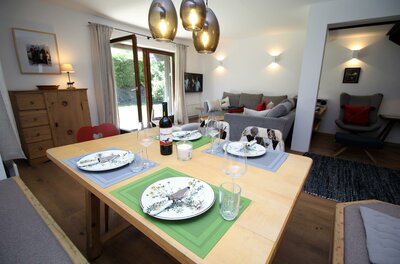 Essbereich im Apartment Kitzkamm Gedeckter Holztisch in einem modernen Wohn- und Essbereich mit Sofa und Terrassenzugang.