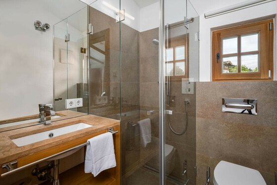 Badezimmer Ski In/Out Asten Modernes Badezimmer mit Waschtisch aus Naturstein, Glasdusche und WC.