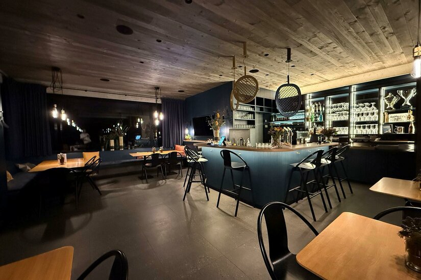 Sport Cafe Eine moderne Bar mit gemütlichen Tischen und Stühlen. Das Beleuchtungskonzept schafft eine einladende Atmosphäre.