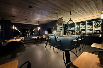 Eine moderne Bar mit gemütlichen Tischen und Stühlen. Das Beleuchtungskonzept schafft eine einladende Atmosphäre.
