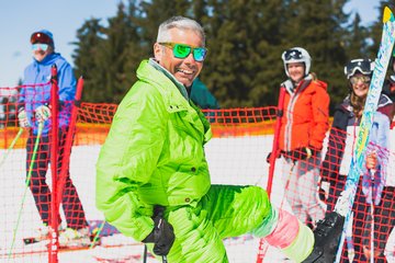 A man in a neon Jacket smiling on the slope