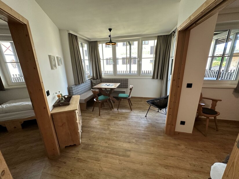 Apartment Eine helle und einladende Wohnung mit Holzböden und großen Fenstern. Der Essbereich ist mit einem Tisch und bunten Stühlen ausgestattet.