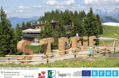 Sommererlebnis Streif Große Holzbuchstaben als Spielgeräte vor einer Almhütte in den Bergen.