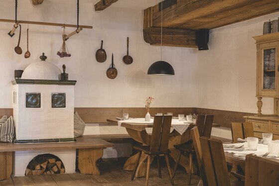 Stube im Wirtshaus Mocking Rustikale Gaststube mit Kachelofen, Holztischen und traditioneller Wanddekoration.