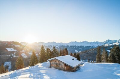 Wirts Hochalm im Winter Holzhütte in verschneiter Berglandschaft bei Sonnenaufgang.