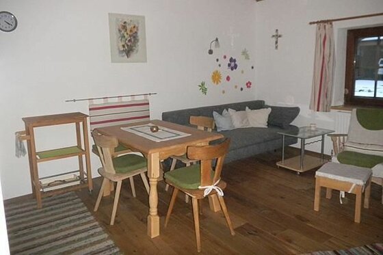 Wohnbereich Seiwaldhof Brandstätter Wohnbereich mit Holztisch, Stühlen, grauem Sofa und Holzboden in einer Unterkunft.