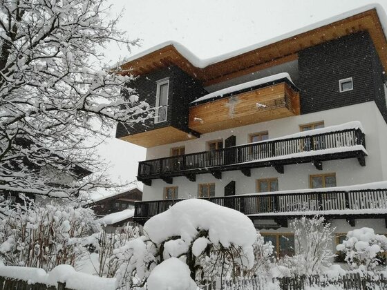 Gästehaus Maier im Winter Mehrstöckiges Gästehaus mit Holzbalkonen und schneebedecktem Dach bei Schneefall.