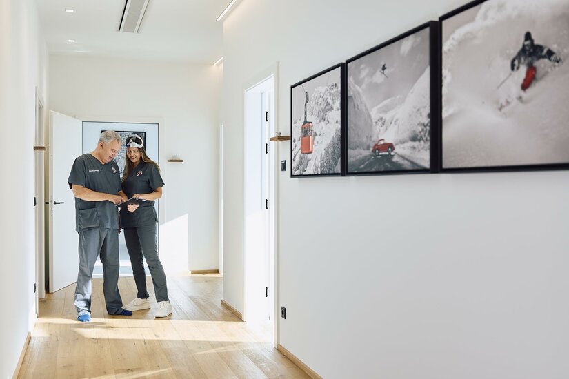 Univ.- Prfo. Dr. Rainer Hahn Ein heller Flur mit modernem Design. Zwei Personen stehen nebeneinander und betrachten Bilder an der Wand.