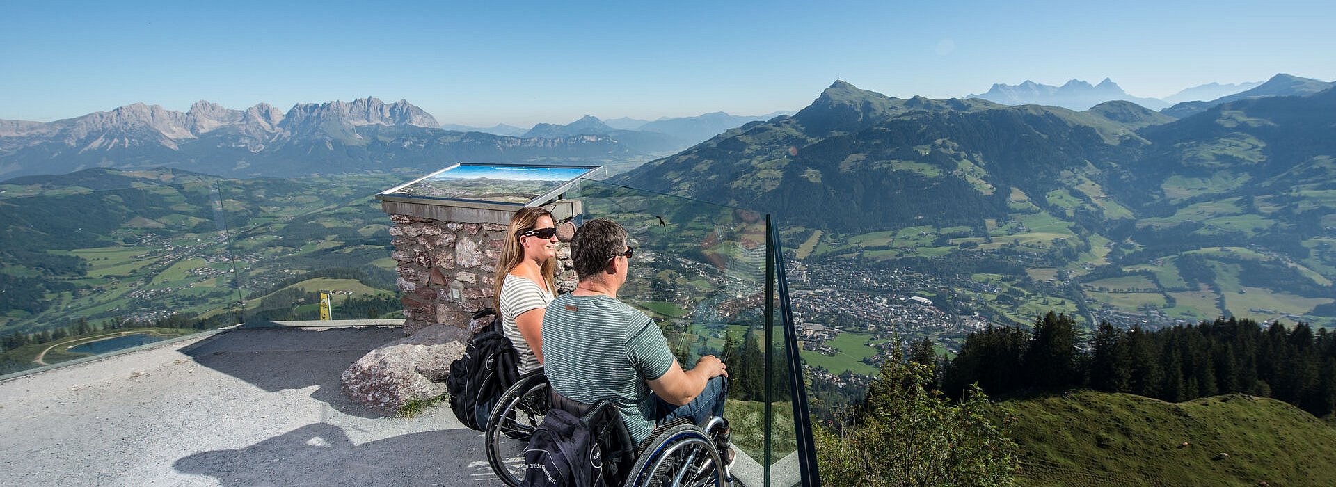 Zwei Menschen im Rollstuhl vor einem Bergpanorama