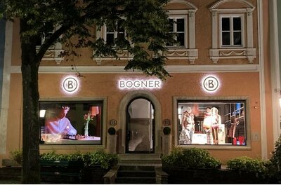 Beleuchtete Fassade eines Bogner-Ladengeschäfts bei Nacht mit Schaufenstern und Logo.