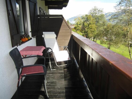 Balkon Herbst Holzbalkon mit Liegestuhl, Tisch und Stuhl vor einer Bergkulisse.