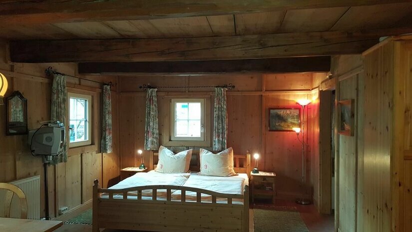 Rustikales Schlafzimmer mit Holzwänden, Doppelbett und Deckenbalken im Angererhof.