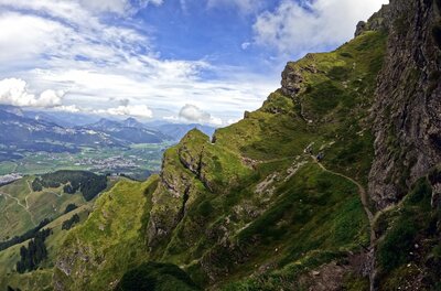 Horn-Gipfel-Höhenweg Schmaler Wanderpfad an einem steilen, grasbewachsenen Berghang mit Blick ins Tal.