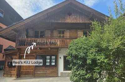 Vorderansicht eines traditionellen Holzhauses mit Balkon und Schaukasten im Erdgeschoss.