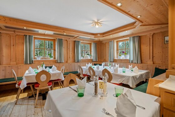 Waldstube im Landhotel Jodlbühel Rustikale Gaststube mit holzgetäfelten Wänden, eingedeckten Tischen und Eckbänken.
