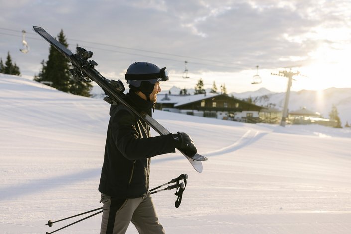 Ein Herr geht mit Skien auf der Piste