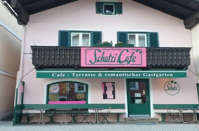 Schatzi Café Kitzbühel Rosa Fassade des Schatzi Cafés in Kitzbühel mit grünen Fensterläden und Außenbestuhlung.