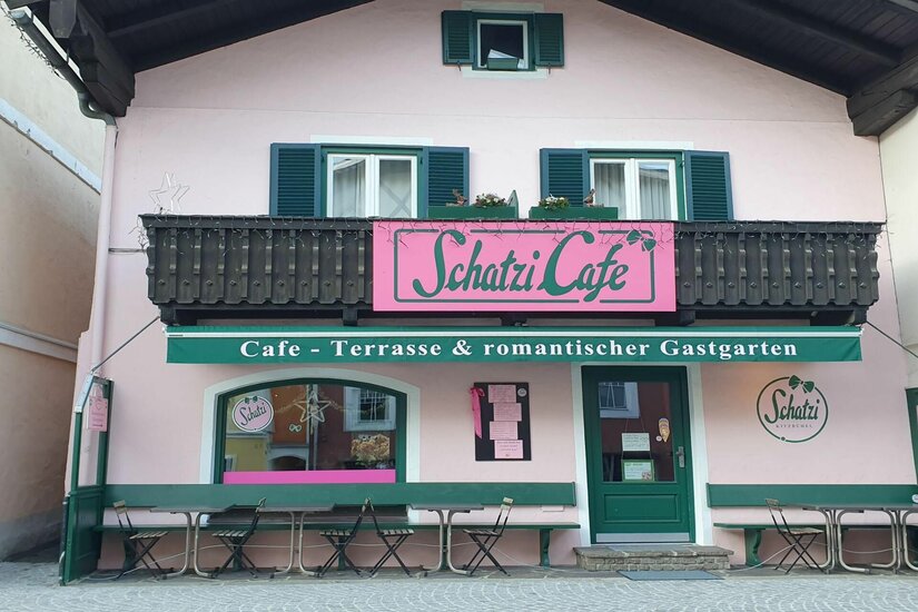 Schatzi Café Kitzbühel Rosa Fassade des Schatzi Cafés in Kitzbühel mit grünen Fensterläden und Außenbestuhlung.